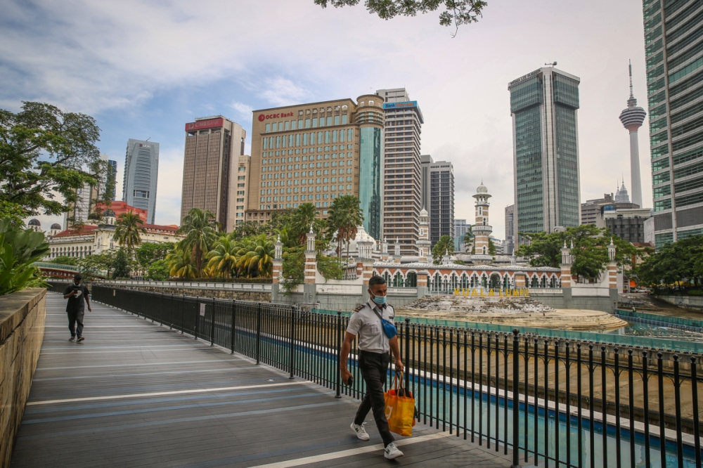 People wearing protective face masks walk on a wooden platform running along the River of Life in Kuala Lumpur on March 4, 2022. — Picture by Yusof Mat Isa
