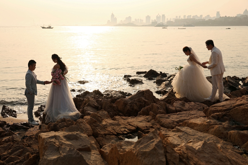 Couples take part in pre-wedding photo shoots by the sea in Qingdao, Shandong province, China April 21, 2024. China is urging colleges and universities to provide ‘love education’ to emphasise positive views on marriage, love, fertility and family, in a bid to boost the country’s flagging birth rate. — Reuters pic 