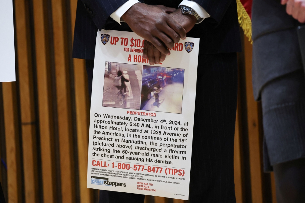 A man holds a poster with security camera still images showing the shooter, during NYPD press conference after the CEO of UnitedHealthcare Brian Thompson was reportedly shot and killed in Midtown Manhattan, in New York City, US, December 4, 2024. — Reuters pic  