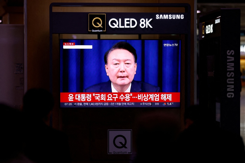  People watch a TV screen broadcasting a news report on South Korean President Yoon Suk Yeol's declaration of martial law and the following announcement that he will lift the martial law, after parliamentary vote, at a railway station in Seoul December 4, 2024. — Reuters pic  