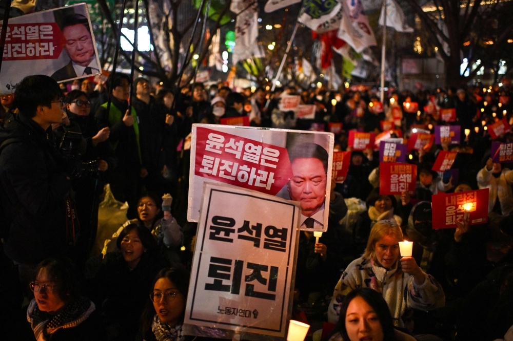 People take part in a candlelight vigil as they call for the resignation of South Korea President Yoon Suk Yeol in Seoul on December 4, 2024. South Korea's opposition moved to impeach Yoon on December 4 after his extraordinary but short-lived imposition of martial law that brought thousands of protesters to the streets. — AFP pic