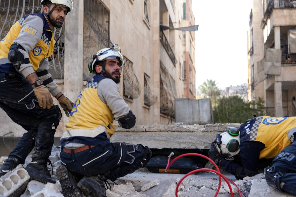 Syrian rescuers known as the 'White Helmets' search the rubble for survivors, following a strike by the Syrian regime airforce that targeted a neighbourhood in Syria's rebel-held northern city of Idlib on December 1, 2024. — AFP pic