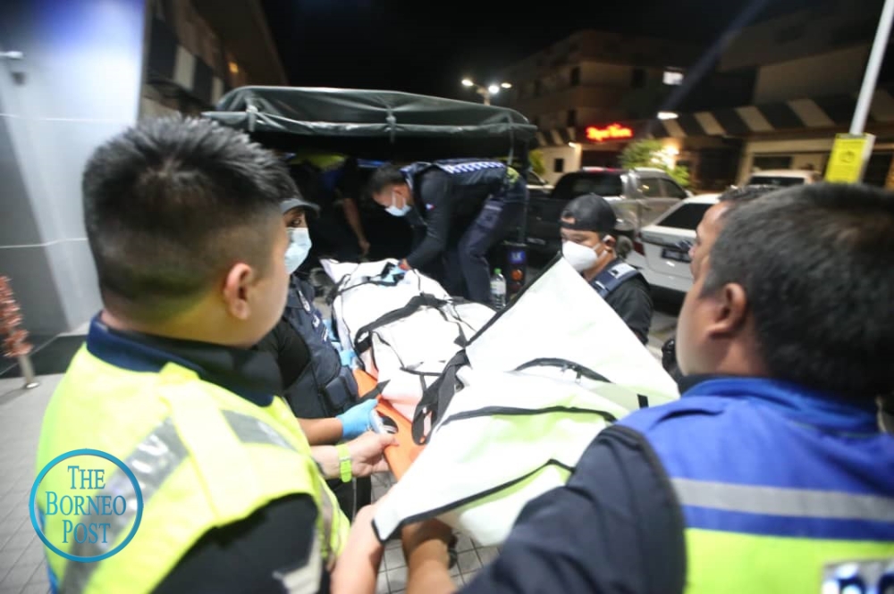 Police personnel carry the suspect’s body from the building on Jalan Undan, near the Inanam Bus Terminal. — The Borneo Post pic