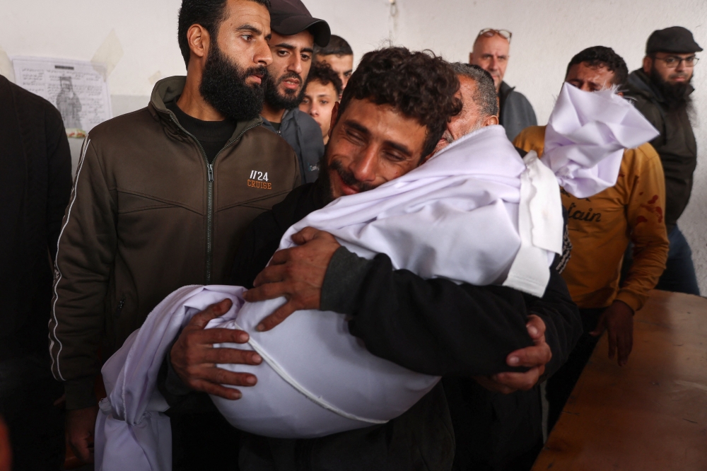A man cries as he holds the body of a two-year-old child who was killed from shrapnel following an Israeli strike in Gaza City, at Al-Ahli Arab hospital, also known as the Baptist hospital on December 5, 2024, as the war between Israel and Hamas militants continues. — AFP pic