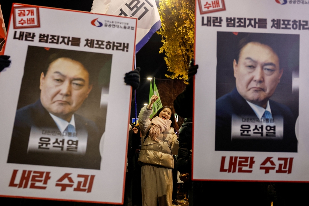 Protesters hold placards during a candlelight vigil to condemn South Korean President Yoon Suk Yeol's surprise declarations of the failed martial law and to call for his resignation in Seoul, South Korea, December 5, 2024. — Reuters pic