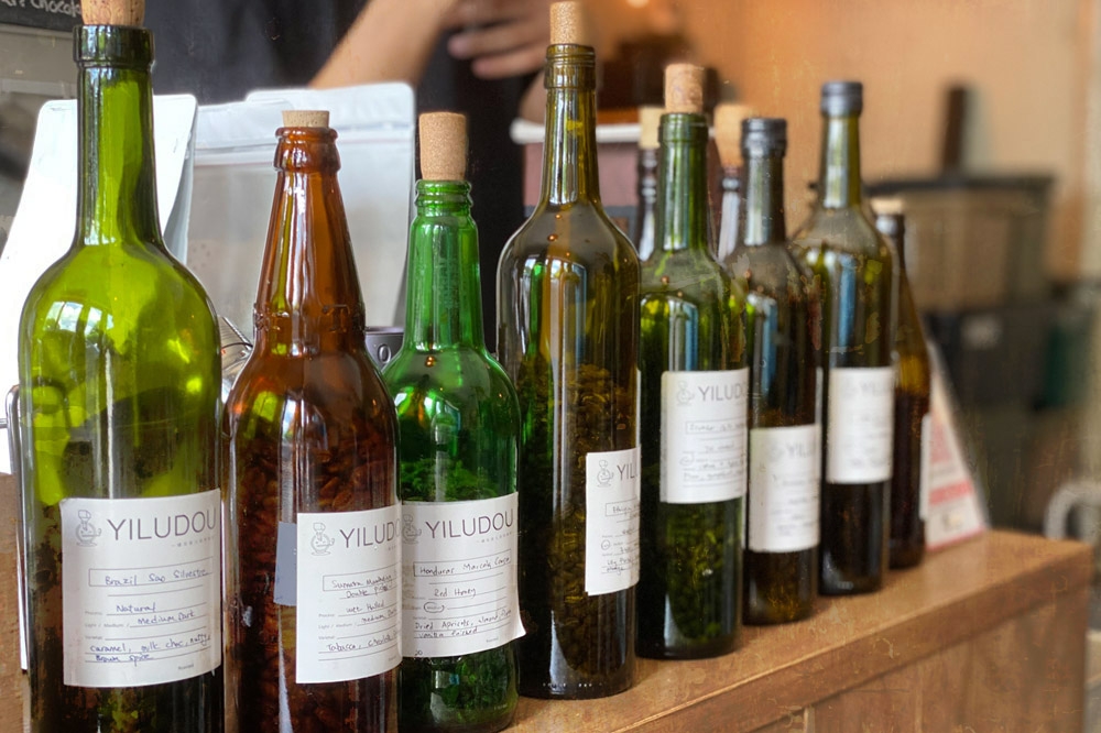 Coloured glass bottles of direct fire roasted coffee beans. — Picture by CK Lim