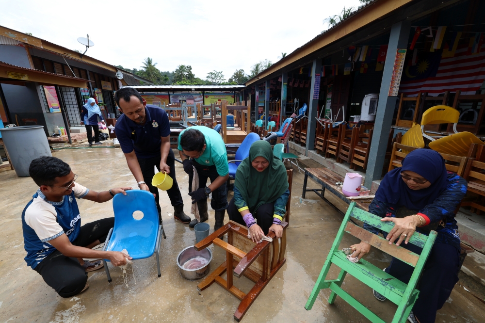Teachers of Sekolah Kebangsaan Lengkuas in Alor Setar clean chairs after the school was affected by recent floods. — Bernama pic