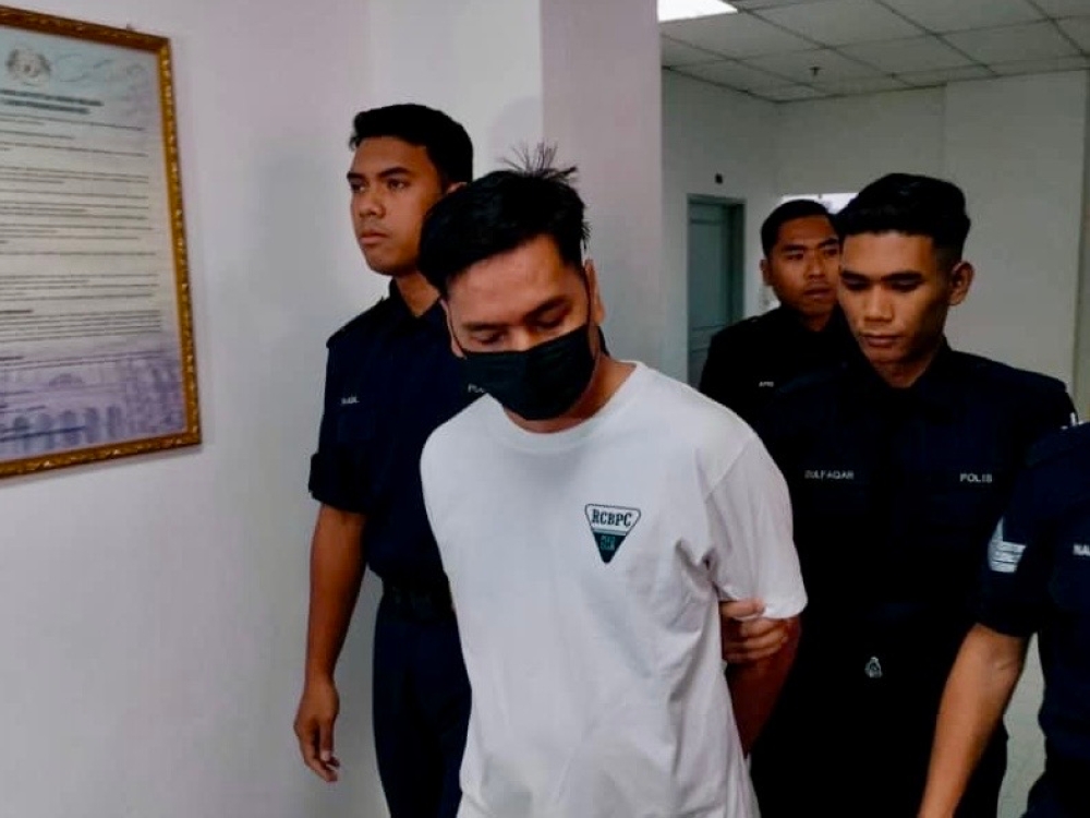 Rosmaini Abd Raof (centre) is escorted by policemen outside the Johor Baru Sessions Court on Dec 9, 2024. — Picture by Ben Tan
