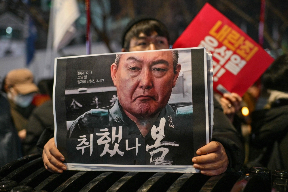A protester holds a poster with an image of South Korea President Yoon Suk Yeol during a candlelight rally in Gwanghwamun in Seoul last week. — AFP pic
