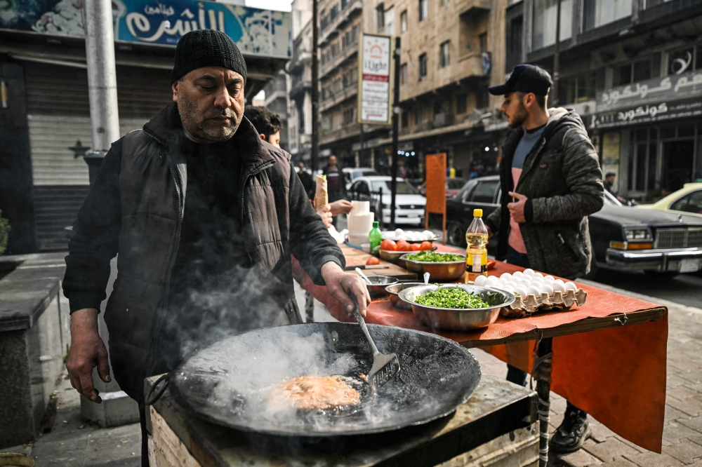 A man prepares fried street food along a street corner in Syria's northern city of Aleppo on December 11, 2024. Islamist-led rebels took the Syrian capital Damascus in a lightning offensive on December 8, ousting president Bashar al-Assad and ending five decades of Baath rule in the country. — AFP pic