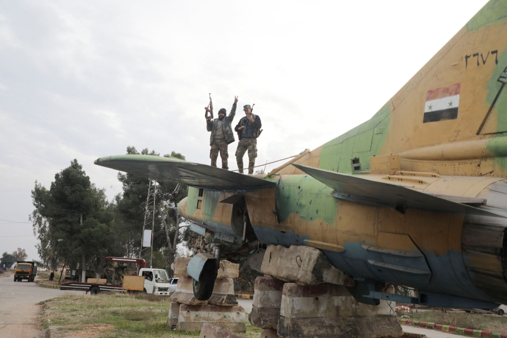 A rebel fighter gestures the victory sign while standing on a military aircraft that belonged to forces loyal to Bashar al-Assad government, inside Hama's military airport, after Syrian rebels battled government forces for control of the key city of Homs on Saturday and advanced towards the capital Damascus as front lines collapsed across the country, throwing President Bashar al-Assad's rule into the balance, in Hama, Syria December 7, 2024. — Reuters pic