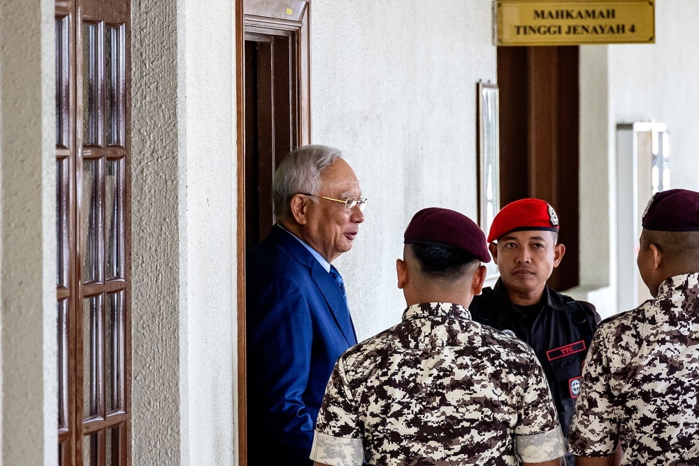 Police officers guard former prime minister Datuk Seri Najib Razak as he is brought to stand trial at the Kuala Lumpur Court Complex on Dec 12, 2024. — Picture by Firdaus Latif   