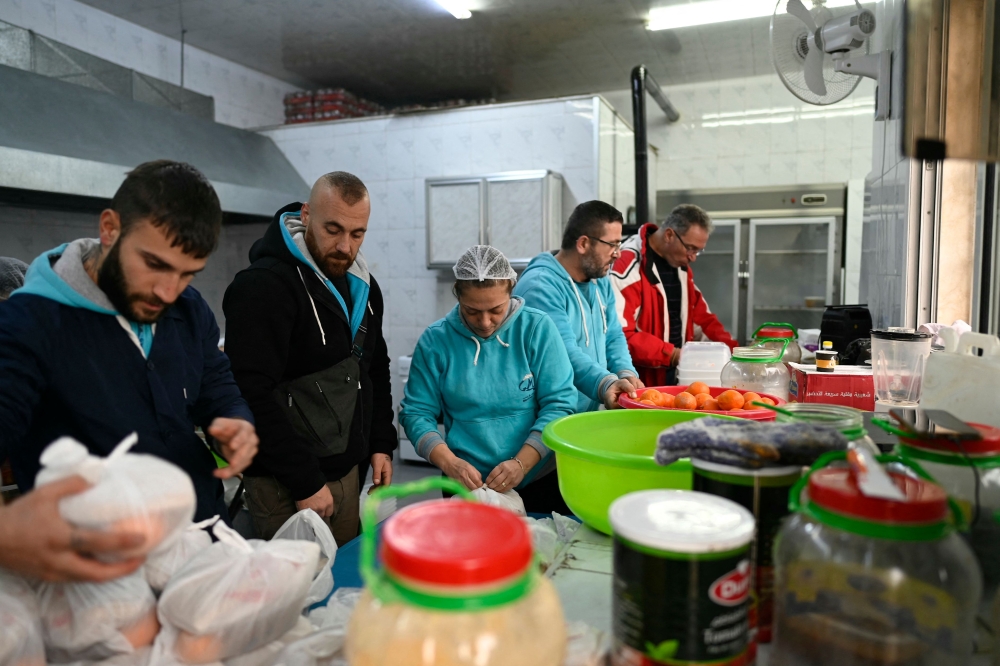 Syrian Christian men and women of the Marist Brothers charitable association prepare food for old people at their quarters in Aleppo on December 12, 2024, as part of a charity project. — AFP pic