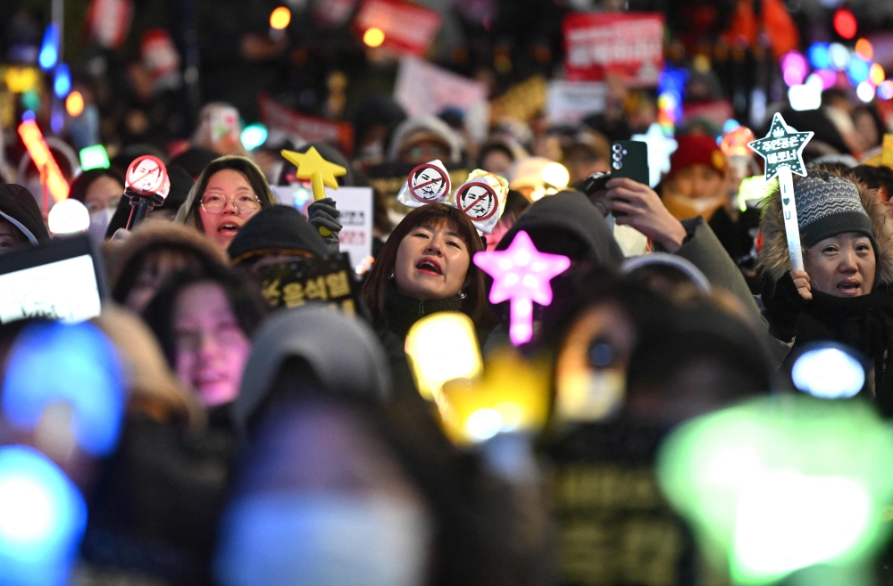 Demonstrators wave light sticks as they take part in a protest calling for the ouster of South Korea President Yoon Suk Yeol on a road near the National Assembly in Seoul on December 13, 2024. — AFP pic