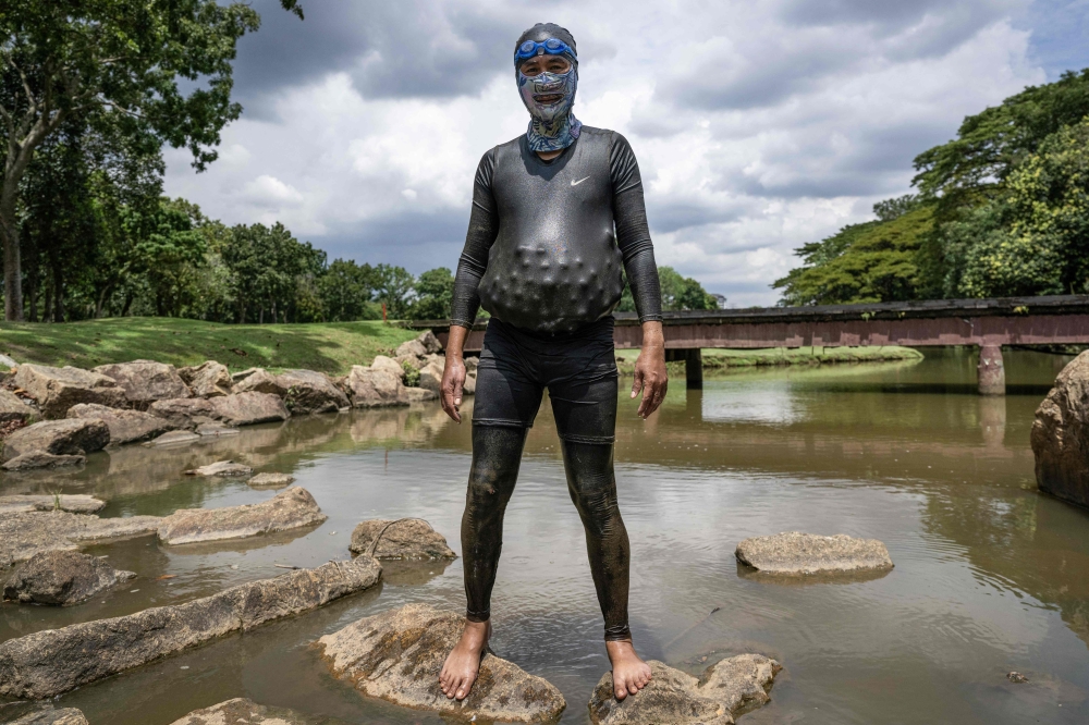 Sumadi Ibrahim poses with golf balls inside his diving suit that he recovered in a pond at a course in Shah Alam, Selangoron Nov 11, 2024. — AFP pic, 