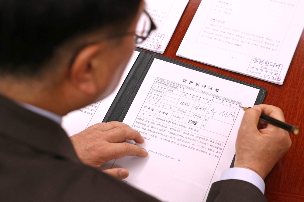 Speaker of the National Assembly Woo Won-shik signs the impeachment resolution against South Korea President Yoon Suk Yeol at the Speaker’s Office in Seoul on December 14, 2024. — AFP pic