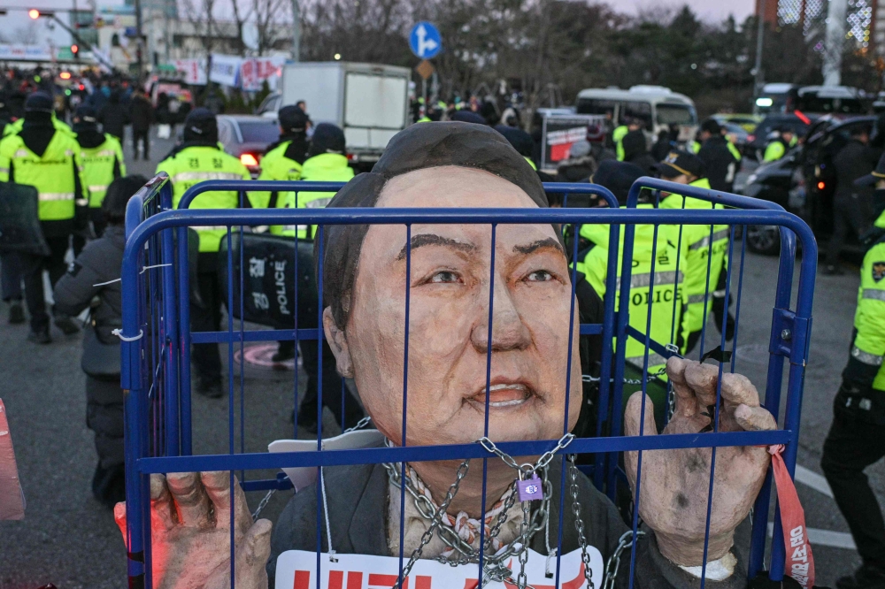 An effigy of South Korean President Yoon Suk Yeol is seen next to police during a protest following the result of the second martial law impeachment vote outside the National Assembly in Seoul on December 14, 2024. — AFP pic