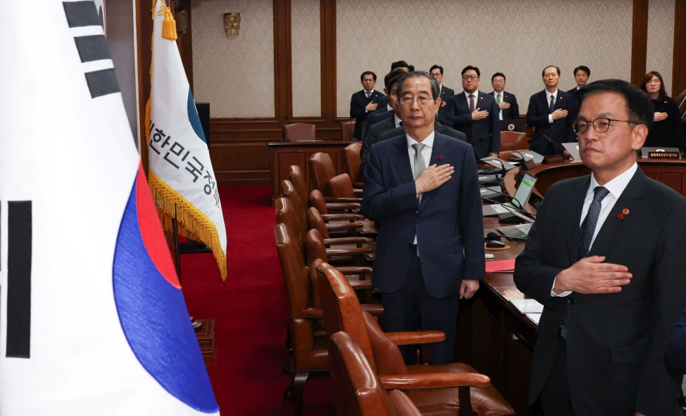 Acting South Korean President and Prime Minister Han Duck-soo salutes to a national flag during a Cabinet meeting at the government complex in Seoul December 14, 2024. — Yonhap pic via Reuters 