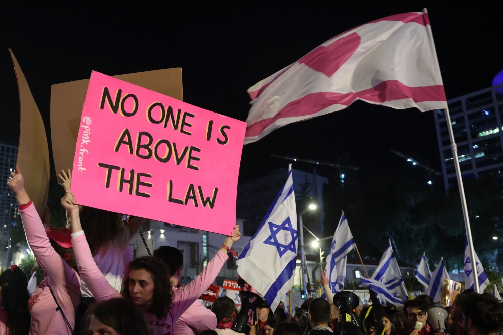 Demonstrators raise placards and Israeli flags during an anti-government protest calling for action to secure the release of Israeli hostages held captive since the October 7 attacks by Palestinian militants in the Gaza Strip, in front of the Israeli Defence Ministry in Tel Aviv on December 14, 2024, amid the ongoing war between Israel and the militant Hamas group. — AFP pic