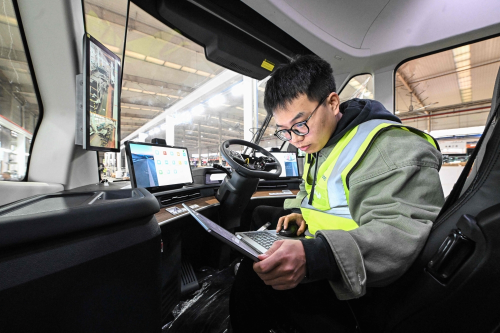 An employee of Chinese electric truck startup Windrose works on an electric truck assembly line at a factory in Suzhou November 18, 2024. — AFP pic