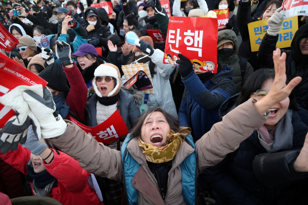 People celebrate after South Korean parliament passed a second impeachment motion against President Yoon Suk-yeol over his martial law decree following a vote, during a rally in front of the National Assembly in Seoul December 14, 2024. — Reuters pic