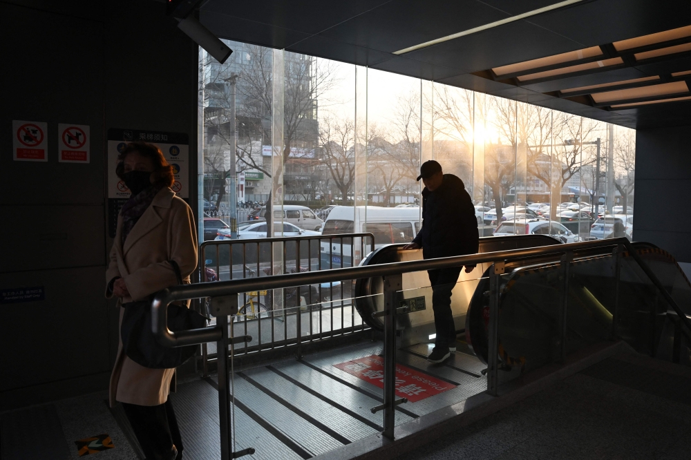 People exit a metro entrance as the sun sets in Beijing December 11, 2024. The city’s rail transit network currently boasts 522 stations, including 98 interchange stations. — AFP pic
