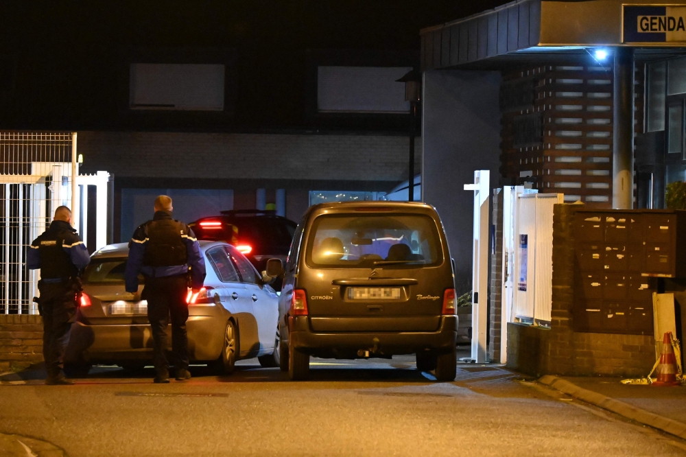 Investigators arrive at a Gendarmerie Police station as French Gendarmes stand next to a vehicle (right) said to be that of the alleged killer, who reportedly turned himself in at the police station, in Ghyvelde, northern France December 14, 2024. Five people were killed on December 14, 2024 in northern France, according to the French Gendarmerie, to which a person surrendered to the authorities at the end of the day, indicating that he committed the murders. — AFP pic