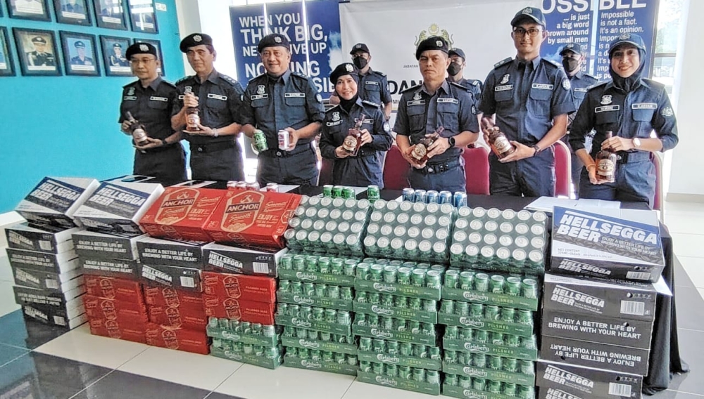 The Sabah Royal Malaysian Customs Department with the seized cartons of duty-unpaid alcoholic drinks. — The Borneo Post pic