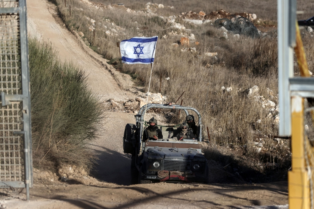 An Israeli military vehicle returns from Syria, crossing the ceasefire line between the Israeli-occupied Golan Heights and Syria, as seen from Majdal Shams in the Golan Heights, December 15, 2024. — Reuters pic 