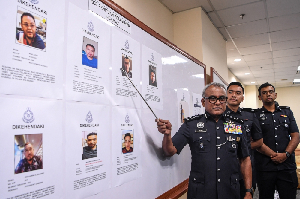 Bukit Aman Commercial Crime Investigation Department (CCID) director Datuk Seri Ramli Mohamed Yoosuf displays photos of seven individuals wanted over the Gigamax investment scam, at Menara KPJ in Kuala Lumpur, on Dec 17, 2024. — Bernama pic