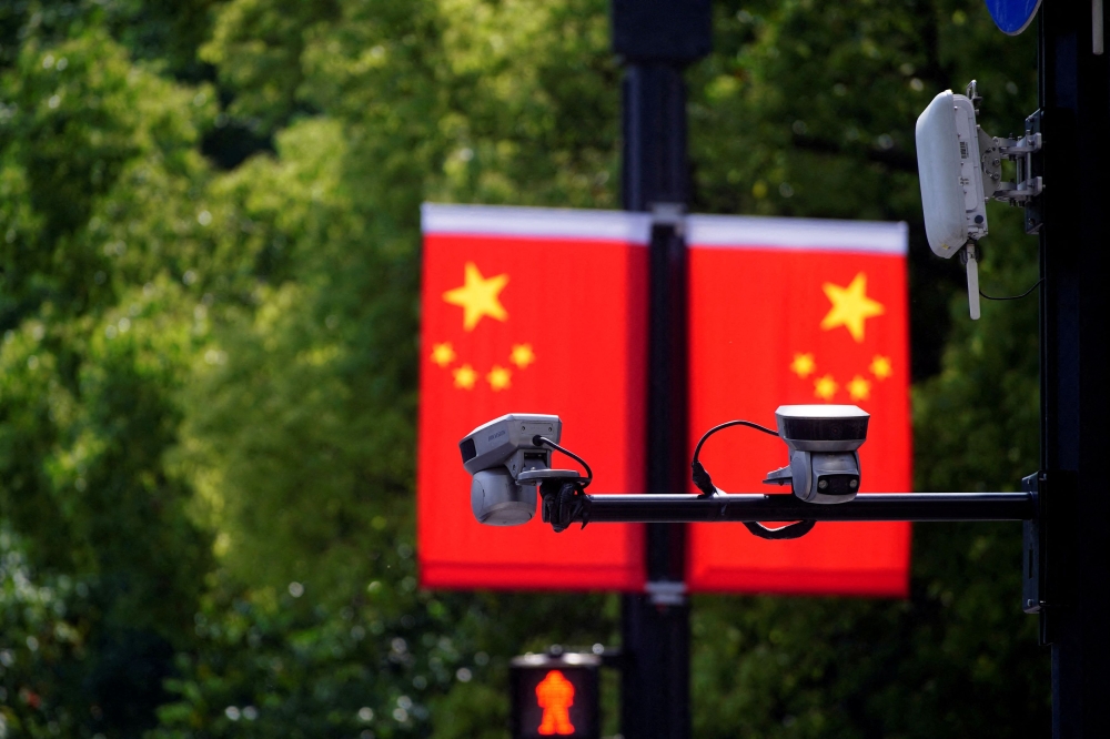 Surveillance cameras are seen in front of a Chinese flag in Shanghai, China on May 5, 2021. — Reuters pic
