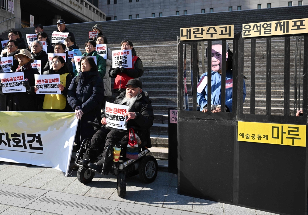 A protester (right) wearing a mask of Yoon Suk Yeol in a mock prison during a demonstration calling for the impeached South Korea president’s ouster in Seoul on December 19, 2024. — AFP pic