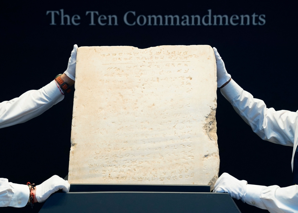 Sotheby’s workers hold one of the most widely known and influential texts in history: the oldest inscribed stone tablet of the Ten Commandments during a press preview at Sotheby’s in New York, on December 9, 2024. — AFP pic 