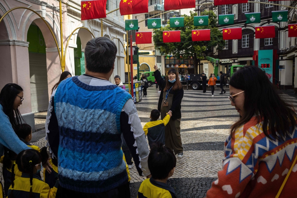 This photo taken on December 13, 2024 shows a kindergarden teacher pointing to Chinese flags while walking with pupils in Senado Square ahead of the 25th anniversary of the city’s handover, in Macau. — AFP pic 