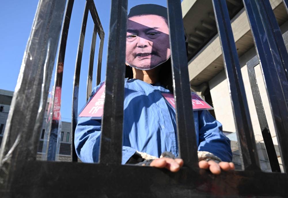 A protester wearing a mask of impeached South Korea President Yoon Suk Yeol performs in a mock prison during a demonstration calling for Yoon's ouster in Seoul yesterday. — AFP