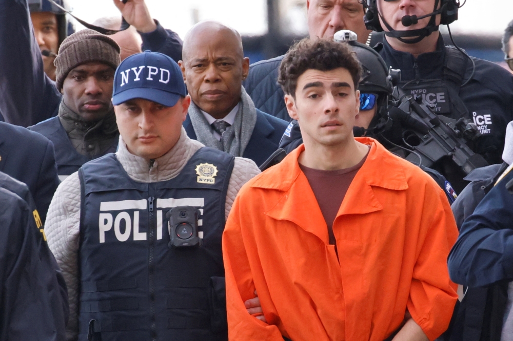 Luigi Mangione, the suspect in the murder of UnitedHealth Group executive Brian Thompson, arrives at a helicopter pad after being extradited from Pennsylvania, as New York Mayor Eric Adams walks behind him, in New York December 19, 2024. — Reuters pic