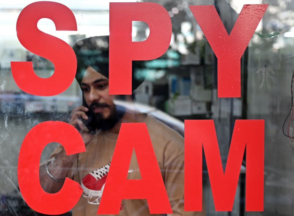 In this photograph taken on December 10, 2024, a vendor selling spy cameras attends a phone call inside his shop at a market in New Delhi. — AFP pic