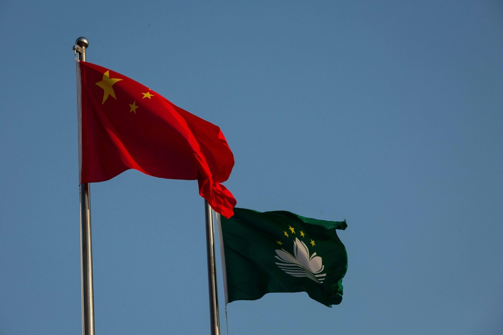 The Chinese and Macau flags during  the flag raising ceremony in Macau on December 20, 2024, on the 25th anniversary of the handover from Portugal to China. — AFP pic