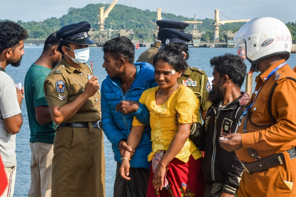 Rohingya refugees (C) interact with police personnel as they arrive at the eastern port of Trincomalee after being rescued by the Sri Lankan navy, on December 20. — AFP