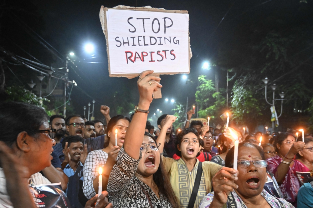 Medical professionals and activists hold posters and candles as they take part in a midnight protest to condemn the rape and murder of a 31-year-old medic, in Kolkata on August 14, 2024. — AFP pic