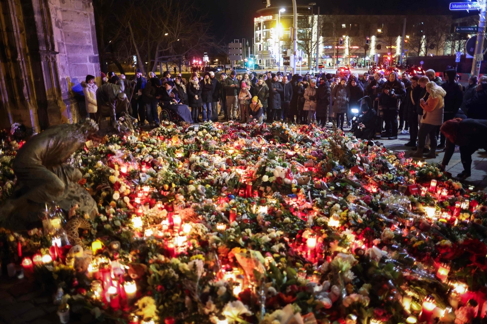 People lay flowers at a makeshift memorial near the site of a car-ramming attack on a Christmas market in Magdeburg that saw over 200 injured. — AFP