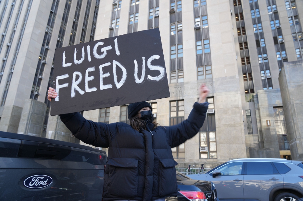 A woman holds a sign in support of Luigi Mangione outside the Criminal Court building in New York December 19, 2024. — AFP pic