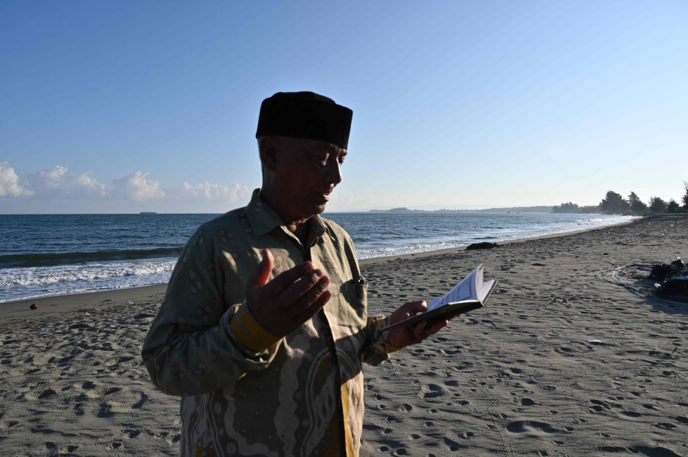 Baharuddin Zubir offers prayers for his relatives who lost their lives in the 2004 Indian Ocean tsunami in Peukan Bada, Aceh province. — AFP
