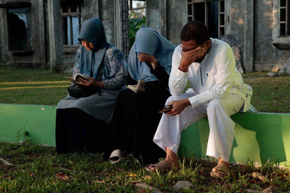 Mourners react as they gather at the Ulee Lheue mass grave, one of the two major mass burial sites where victims of the 2004 Indian Ocean tsunami were laid to rest, in Banda Aceh. — AFP
