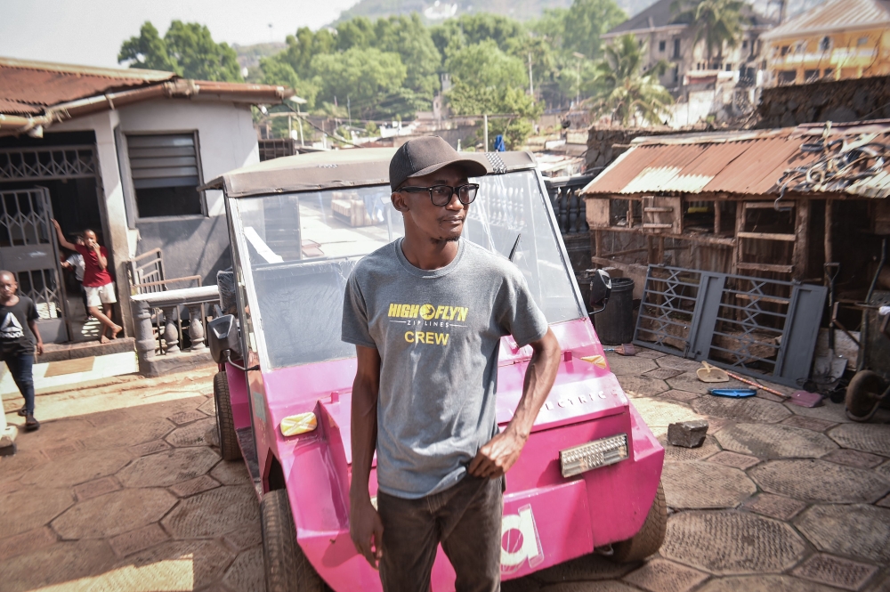 Self-thought innovator James Samba stands in front of an eco-friendly electric vehicle he made from scrap metals in Freetown on December 18, 2024. — AFP pic