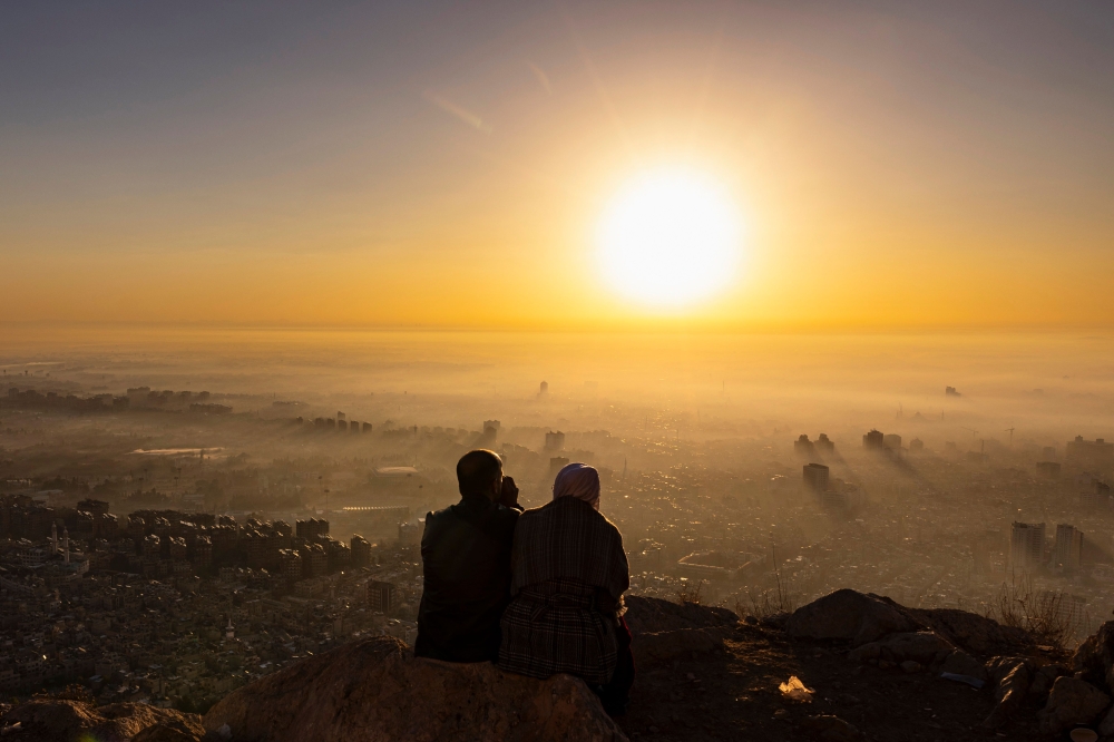 A couple watches the sunrise from a spot on Mount Qasioun. — AFP pic
