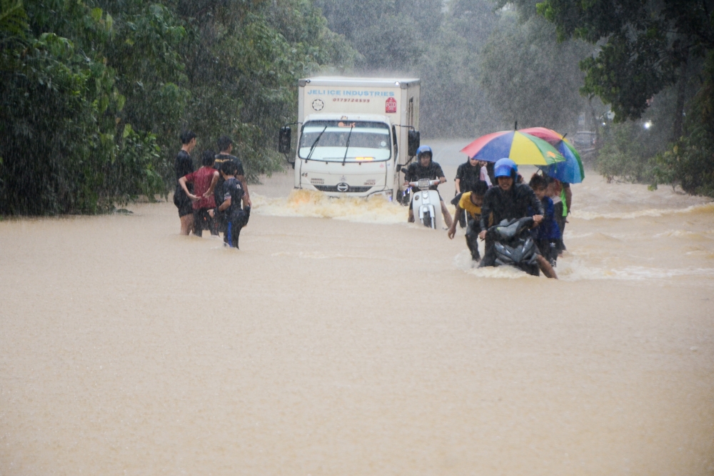 Tanah Merah residents and road users wade through floodwaters on the main road in Kampung Kelewek, Lawang, Batu Gajah on December 29, 2024 due to rising floodwaters from 8am. — Bernama pic