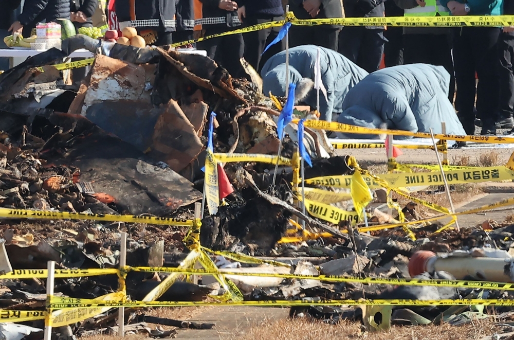 Mourning relatives bow at the site where a Jeju Air Boeing 737-800 aircraft crashed and burst into flames at Muan International Airport. — AFP