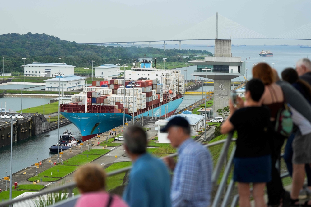 Tourists look at a cargo ship sailing through the Agua Clara Locks of the Panama Canal in Colon City, Panama, on December 28, 2024. — AFP pic