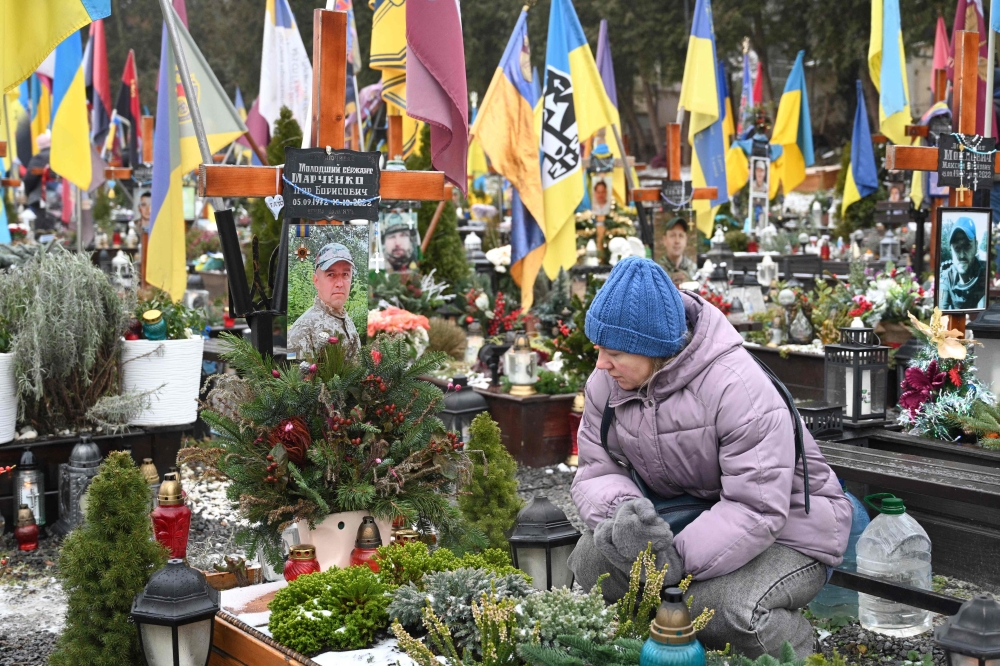 A woman mourns next to the grave of a fallen Ukrainian soldier at the Lychakiv Military Cemetery in Lviv, on December 28, 2024, amid the Russian invasion of Ukraine. — AFP pic